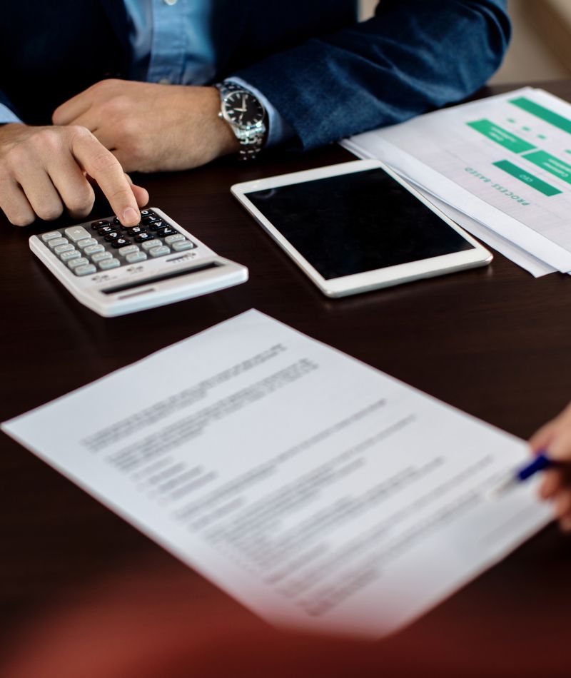 Gestión de contratos de energía. Un chico con una calculadora, una tablet y unos contratos de luz.